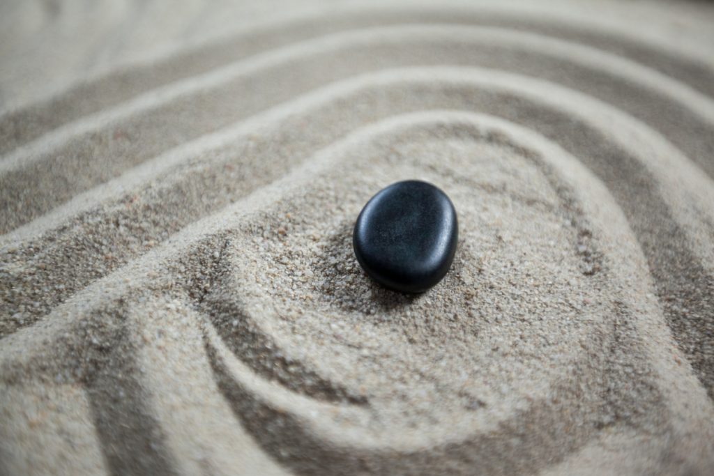 jardin zen avec du sable ratissé et une pierre noire