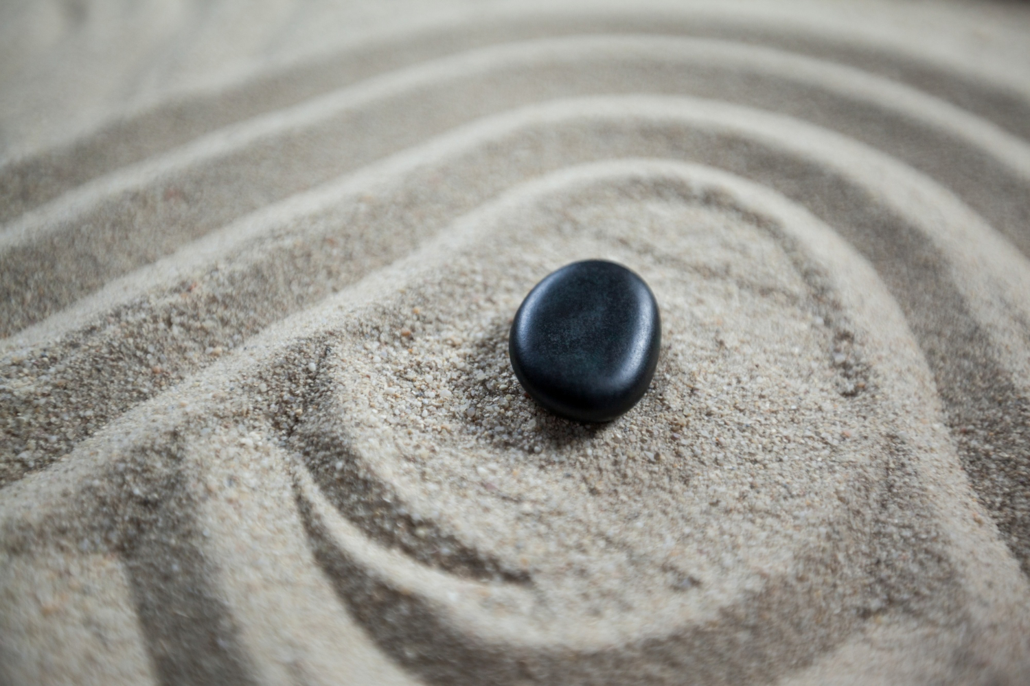 jardin zen avec du sable ratissé et une pierre noire