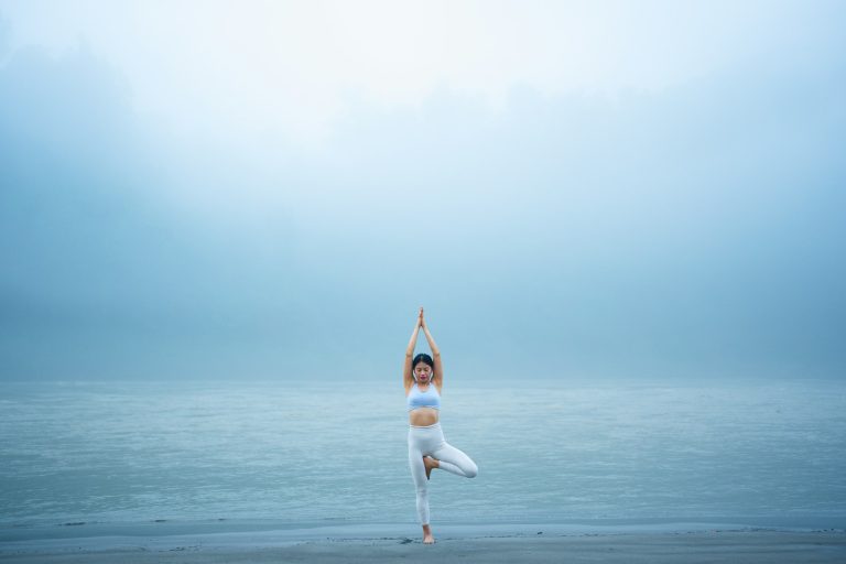 Femme en posture de l'arbre, pratique le yoga pilates en extérieur
